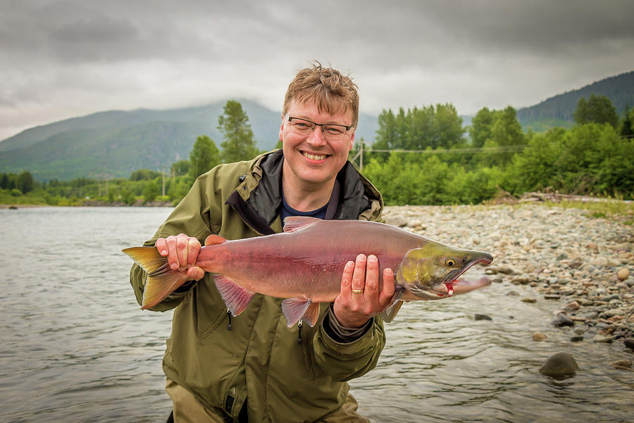 A happy fisherman proudly holding up a sockeye salmon Photograph