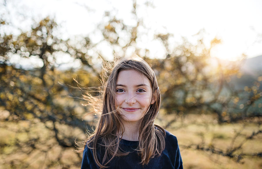 A happy small girl standing outdoors in nature in autumn. Photograph by Halfpoint Images