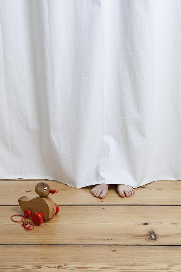 A hiding childs feet sticking out from under a hanging sheet Photograph by Halfdark