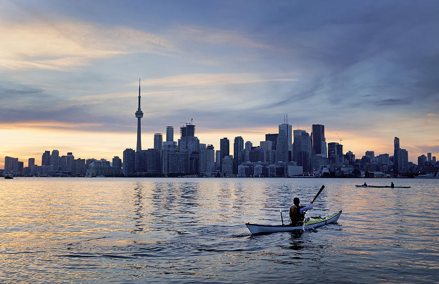A kayaker in front of a city skyline Photograph by Russell Monk
