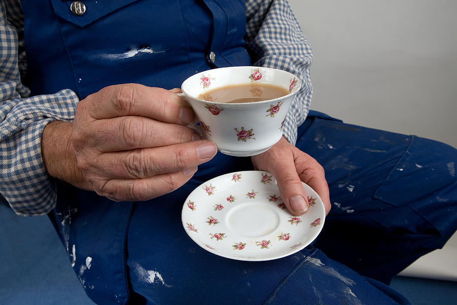A labourer holds a delicate cup of tea and saucer Photograph by GSO Images