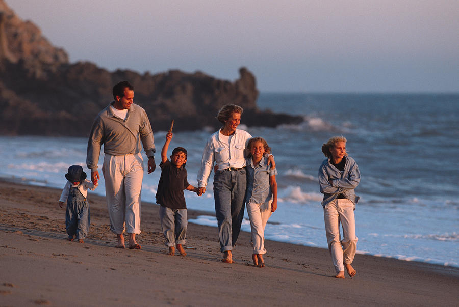A Large Family Walks Along The Beach At Sunset Photograph by Photodisc