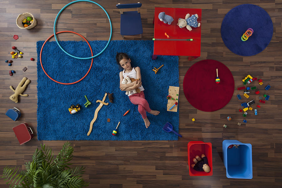 A little girl lying on a rug hugging stuffed animals, overhead view Photograph by fStop Images - Halfdark