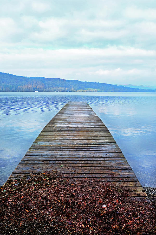 A long wooden jetty on a lake, looking out over a straight out o ...