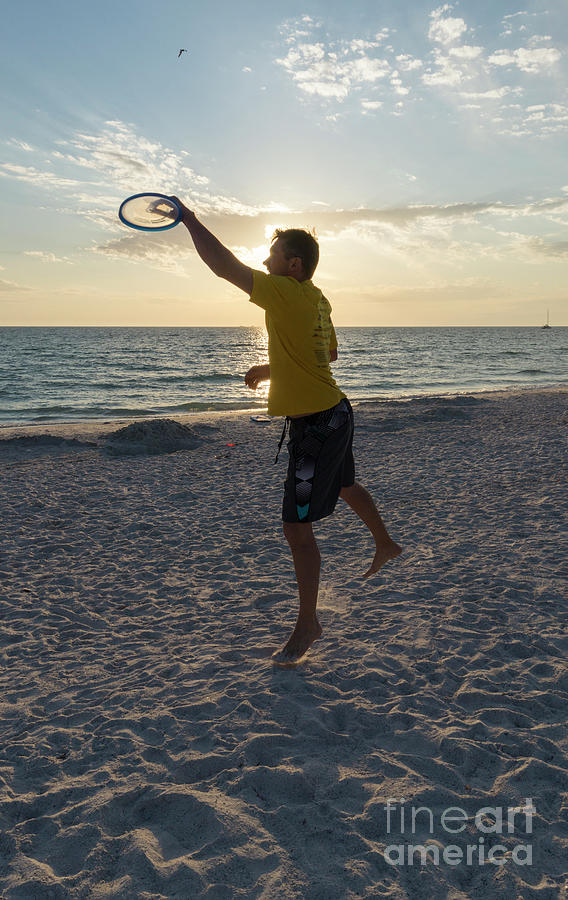 A man catches a flying disk on the beach at sunset at Anna Maria Photograph by William Kuta