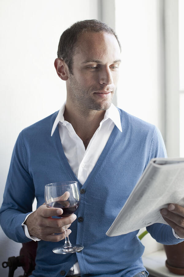 A man drinking a glass of wine and reading a magazine Photograph by fStop Images - Andreas Stamm