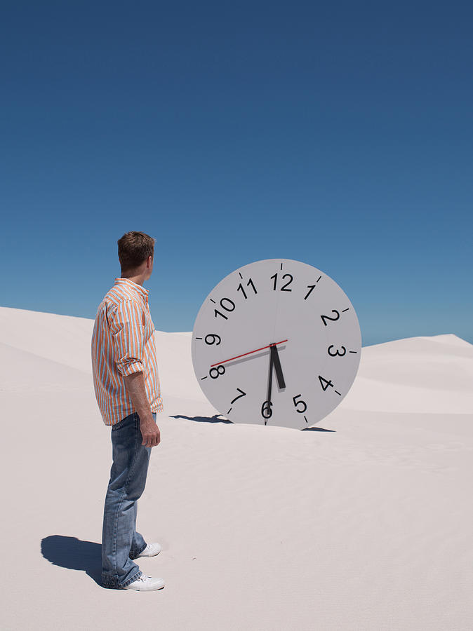 A man looking at a clock in the desert Photograph by Robert Daly