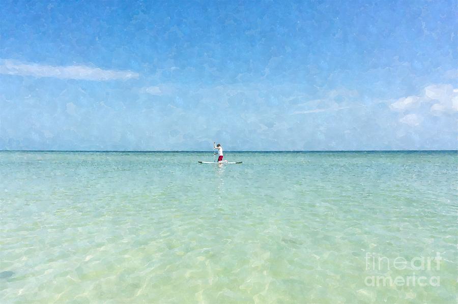 A man rides a paddleboard in the shallow waters near the city pier on Anna Maria Island in Florida Photograph by William Kuta