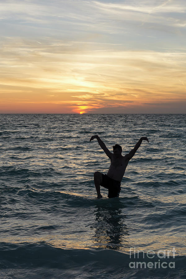 A man strikes a karate pose in the water at sundown at Anna Mari Photograph by William Kuta
