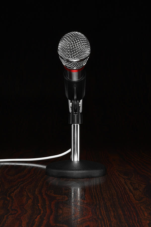 A microphone in a stand, on a wooden desktop Photograph by Creative Crop