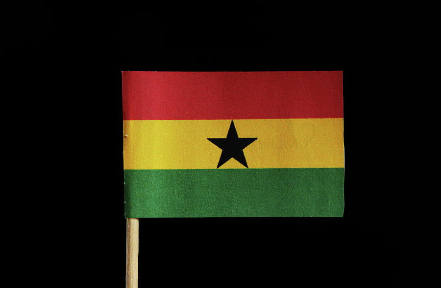 A national flag of Ghana on toothpick on black background. A horizontal triband of red, gold and green with a black star in centre Photograph by Vaclav Sonnek