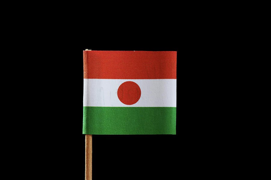 A official flag of Niger on toothpick and on black background. Niger is located in Africa continent. Photograph by Vaclav Sonnek