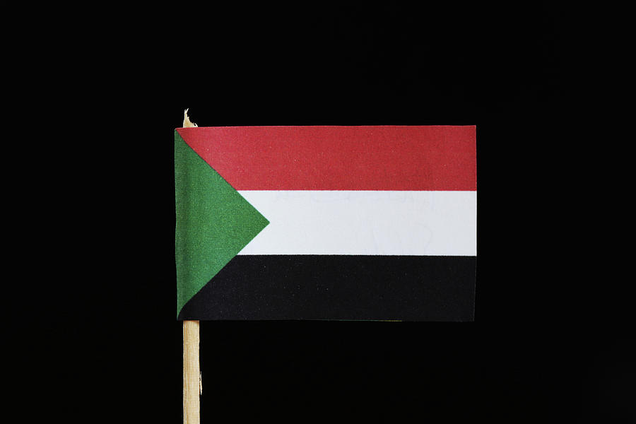A official flag of Sudan on toothpick on black background. Flag consists of a horizontal red, white, black tricolour with a green triangle Photograph by Vaclav Sonnek