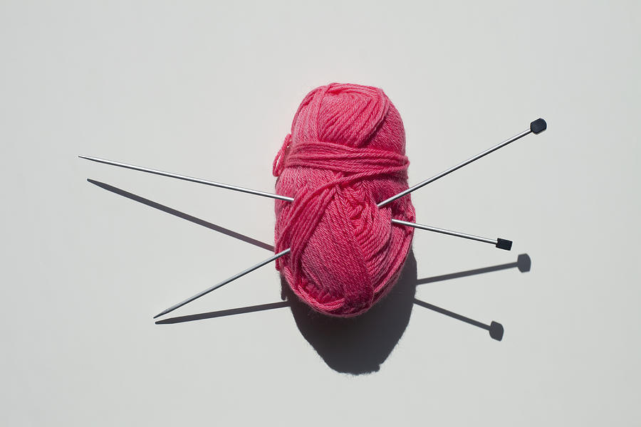 A pair of knitting needles stuck into a ball of yarn Photograph by Larry Washburn