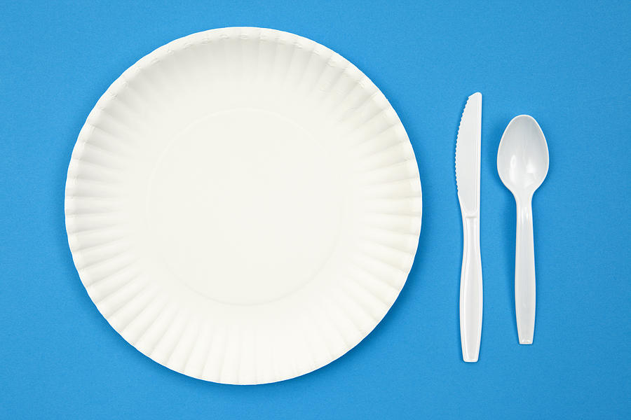 A paper plate next to plastic utensils on a blue table Photograph by JulNichols