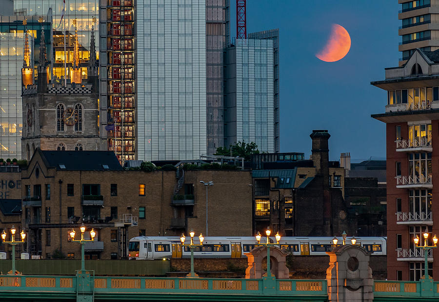 A partial lunar eclipse in London with illuminated Southwark bridge and