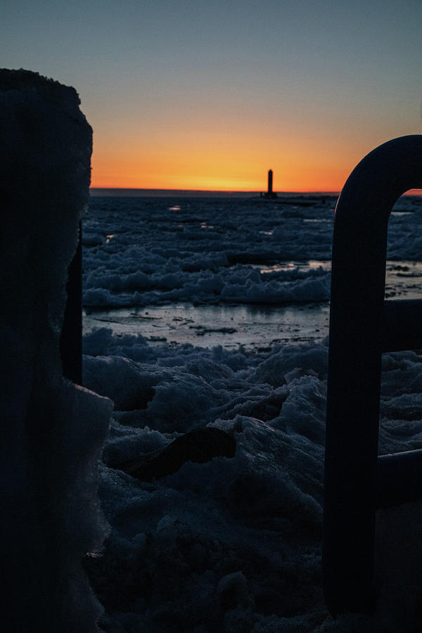 A peak through the Holland Michigan Pier railing during winter sunset over Lake Michigan Photograph by Eldon McGraw