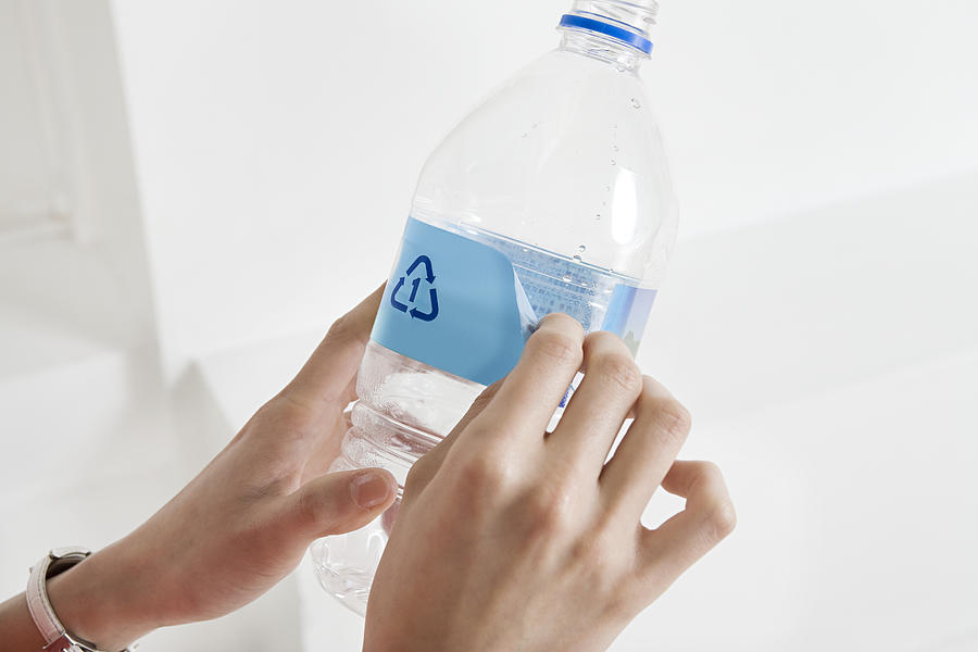 A person peeling off a label off a bottle Photograph by Image Source