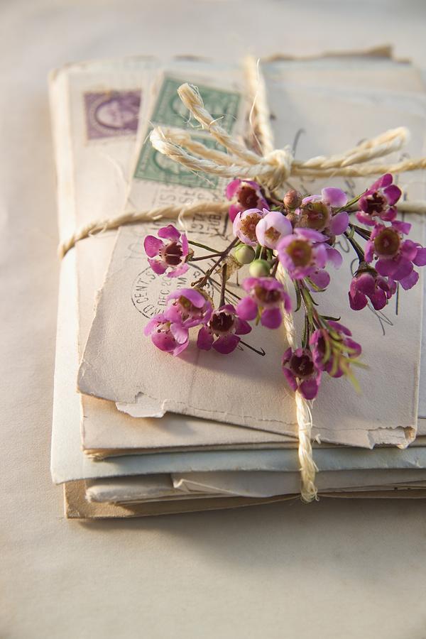 A pile of letter tied with twine and decorated with flowers Photograph by Tetra Images