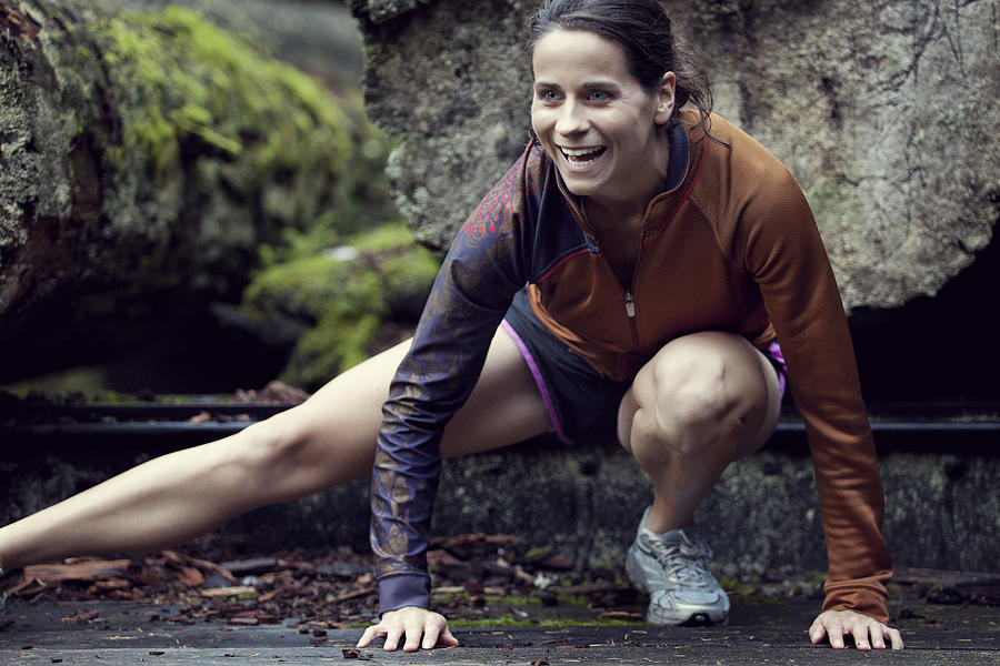 A portrait of a runner stretching in front of old growth trees at Point Defiance. Photograph by Brandon Sawaya