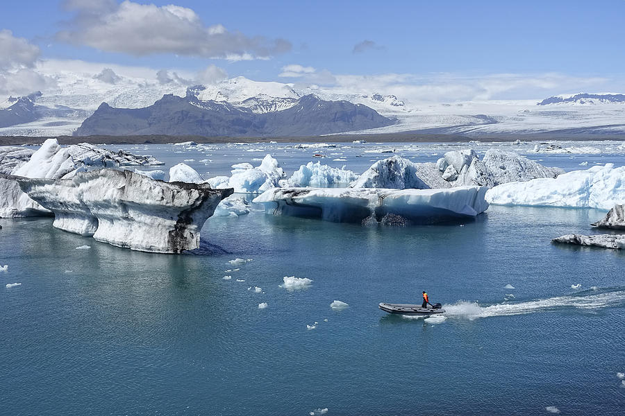 A rigid inflatable boat threads its way through icebergs in the glacier lagoon at Jokulsarlon, Iceland Photograph by Peter Mulligan