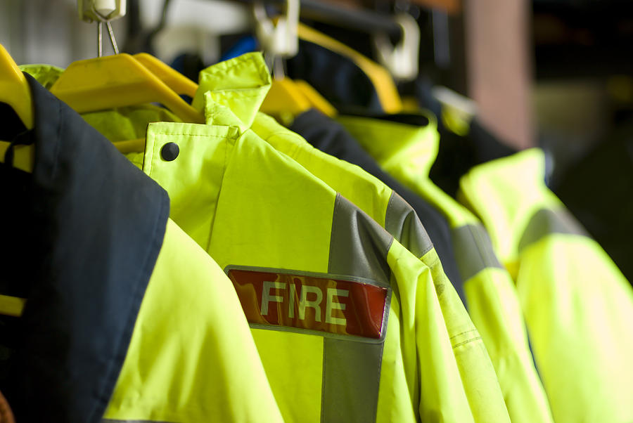 A row of British Firefighter jackets neatly hung up for use Photograph by Southerlycourse