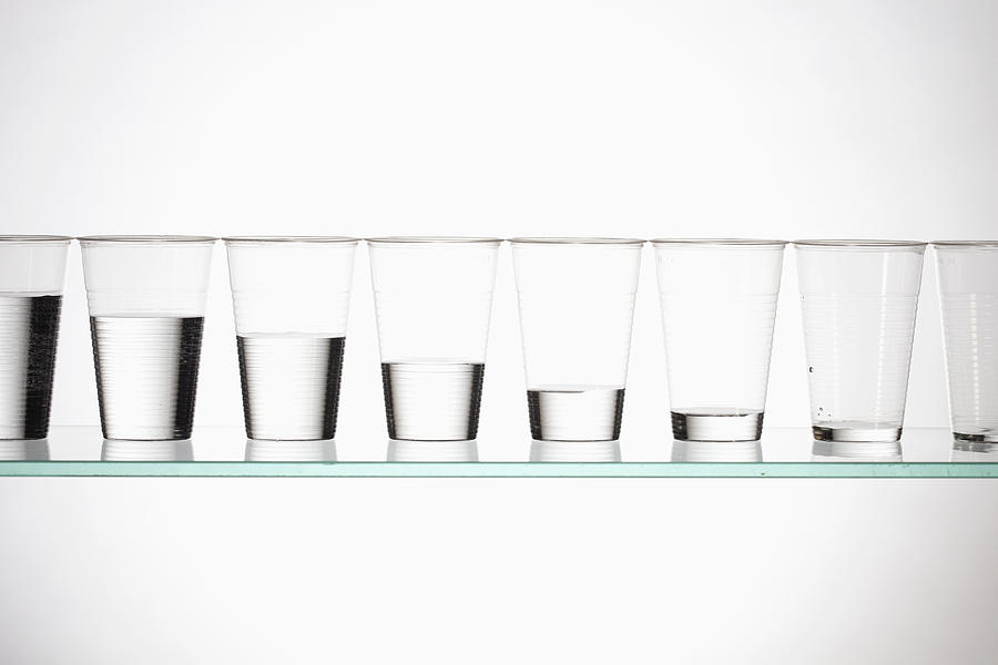 A row of glasses with varying amounts of water descending from full to empty Photograph by Larry Washburn
