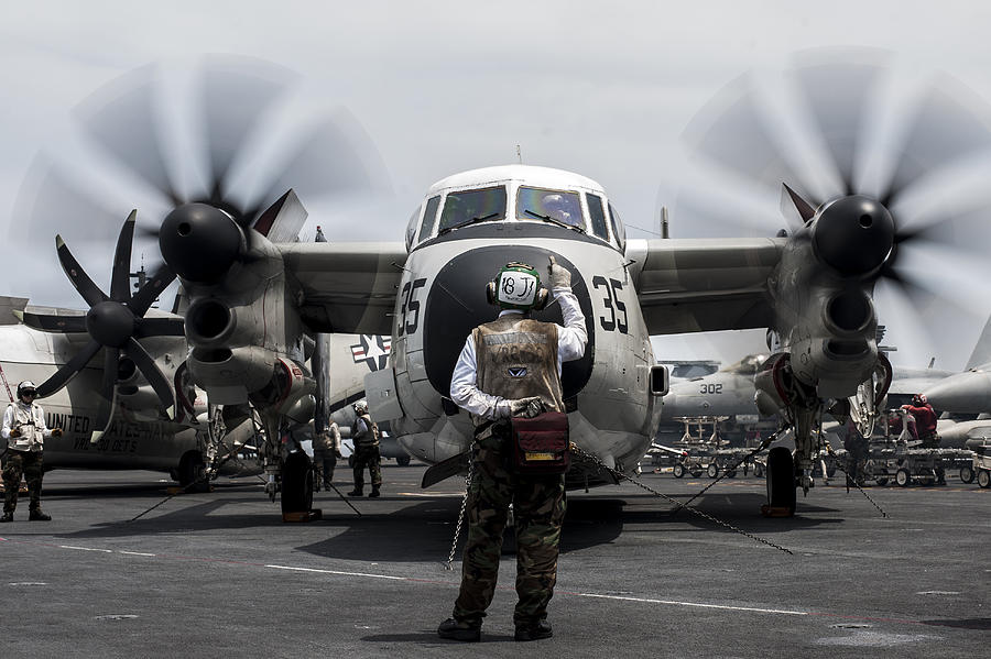 A Sailor directs a C-2A Greyhound on the flight deck of USS George Washington. Photograph by Stocktrek Images