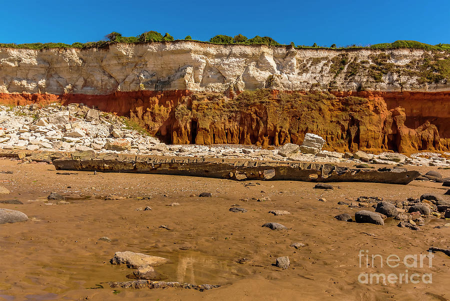 A shipwreck sits prominently in front of a chalk rockfall on Old ...