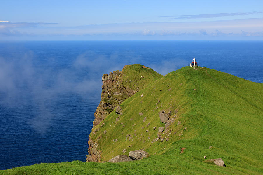 A small lighthouse on top of a grassy steep cliff high above the sea Photograph by Rainer Grosskopf