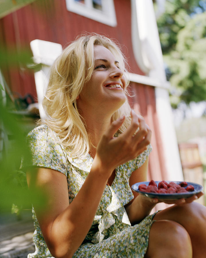 A smiling woman eating strawberries Sweden. Photograph by Per Eriksson