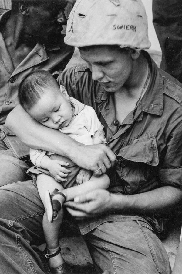 A soldier whose helmet says Swierk holds a Vietnamese child during ...