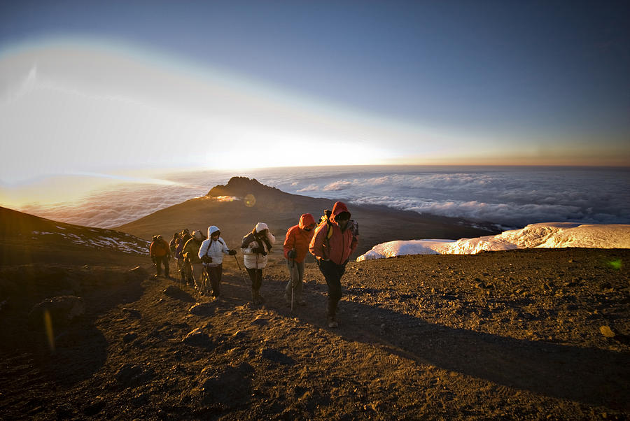 A team of hikers approach the summit of Mt. Kilimanjaro at sunrise after trekking six hours through the night. Photograph by R. Tyler Gross
