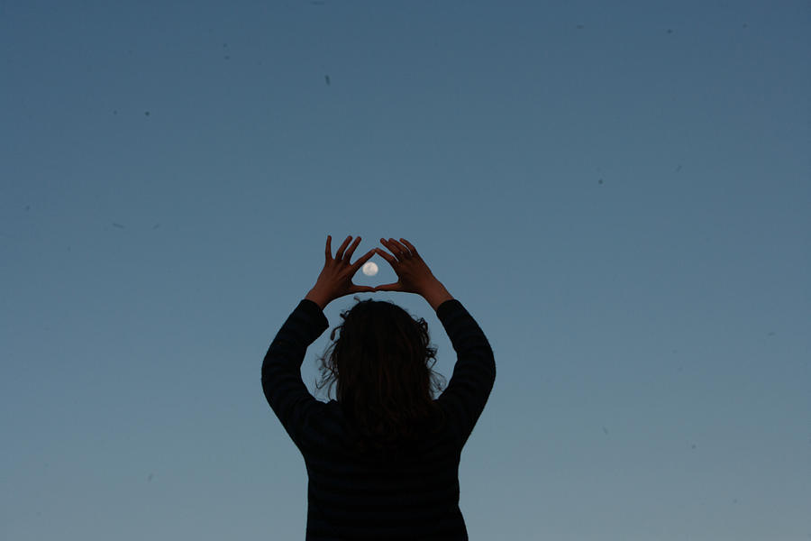 A teenage girl encircles a full moon with her fingers in the crepuscular ight Photograph by Hello World