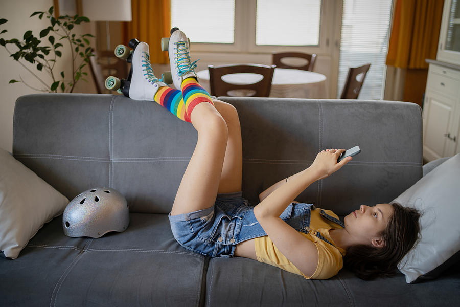 A teenager lyiing  down with her legs resting on the back of a sofa Photograph by Vladimir Vladimirov