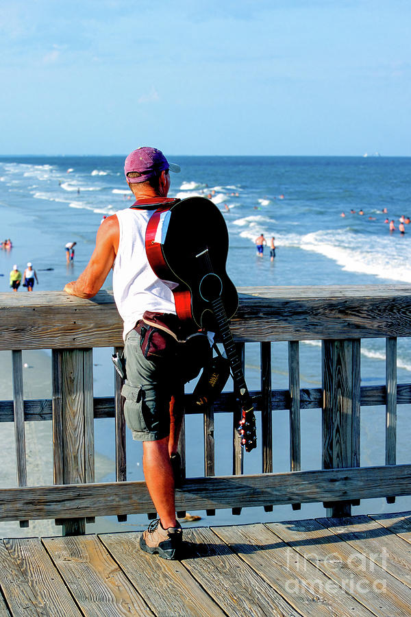 A troubadour looks out on the Atlantic beach from the pier on Ty Photograph by William Kuta