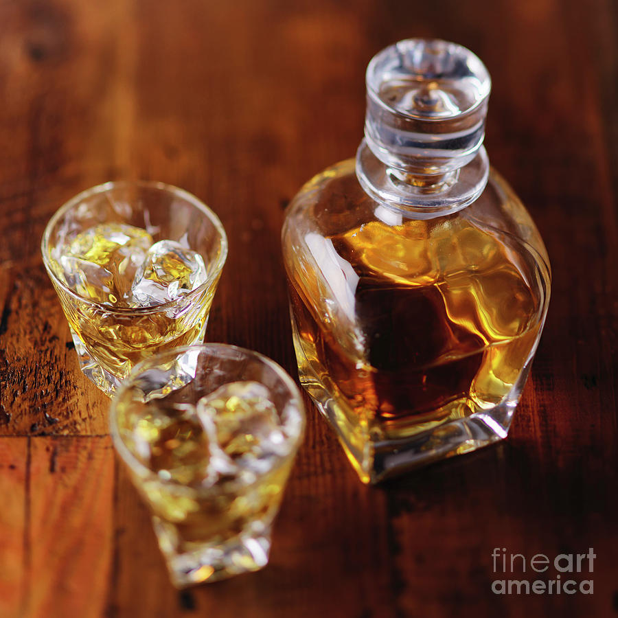 A Whiskey Bottle And Two Glasses Of Scotch On The Rocks On A Woo Photograph