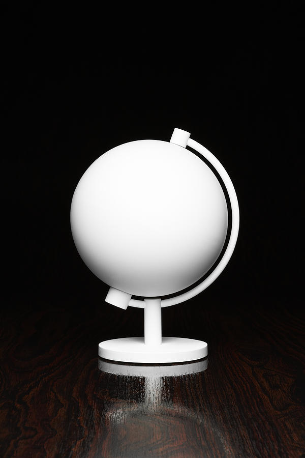 A white globe on a desktop Photograph by Creative Crop