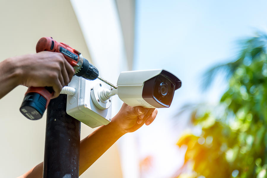 A Wireless CCTV camera setting outside building with white box water poof with sun blur background. Photograph by DSCimage