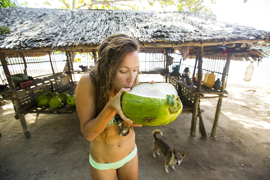 A woman drinking from a young fresh coconut. Photograph by Jordan Siemens