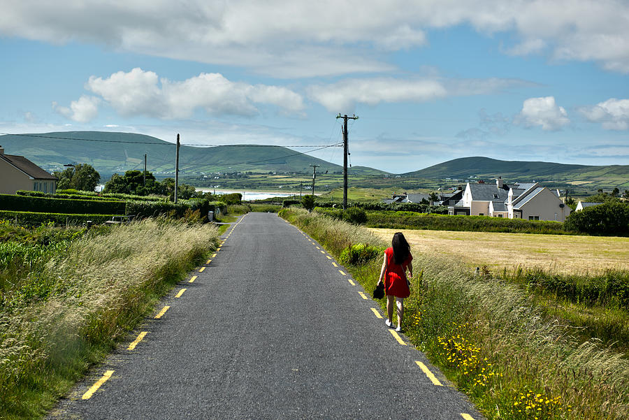 A woman in a red dress walking on roadside of Waterville in Ireland Photograph by Feifei Cui-Paoluzzo