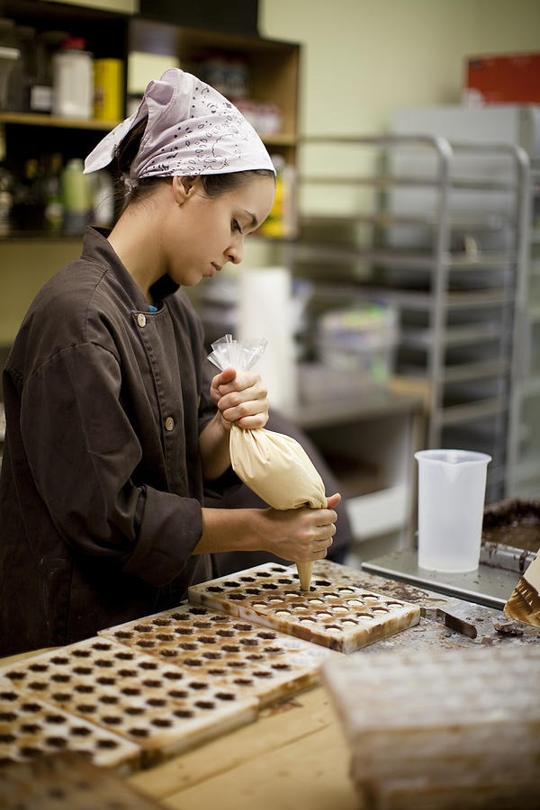 A woman makes chocolate bonbons in an industrial kitchen Photograph by Twohumans
