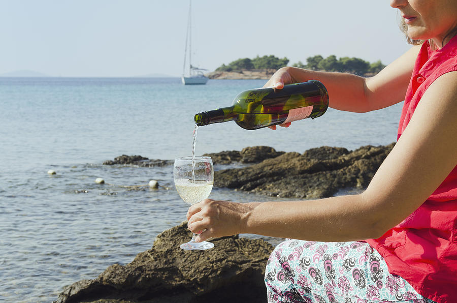 A woman pouring wine into a glass by the sea Photograph by Otto Stadler