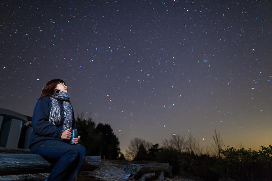 A woman sitting on a bench looking up at stars Photograph by Trevor Williams