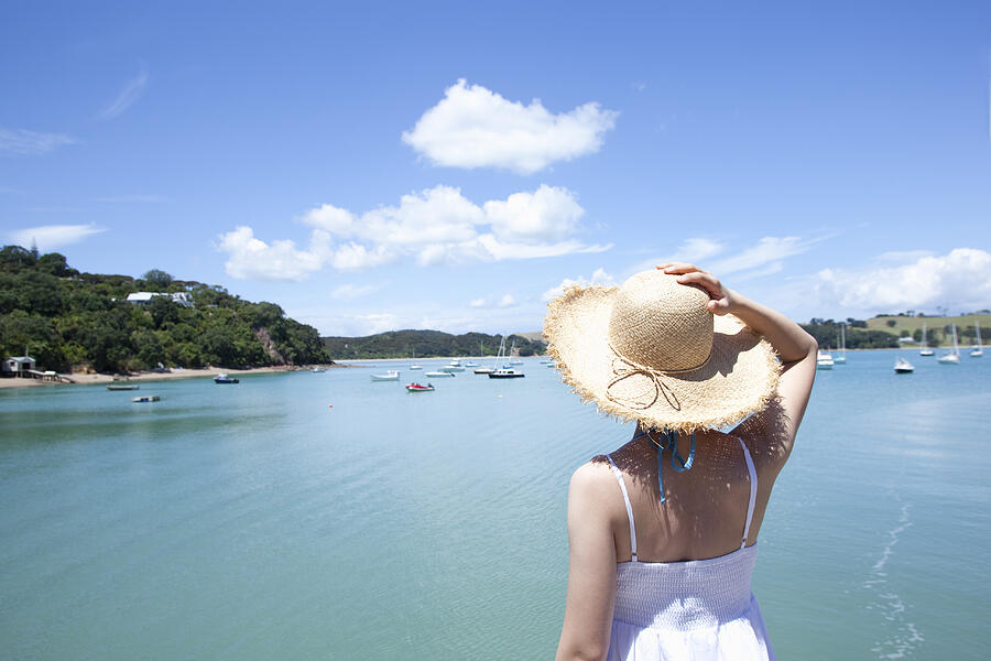 A woman with a straw hat looking at the sea. Photograph by Yasuhide Fumoto