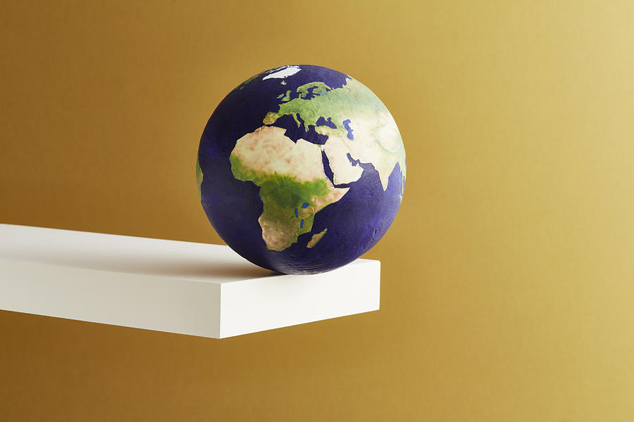 A world globe balanced on the edge of a shelf Photograph by Richard Drury