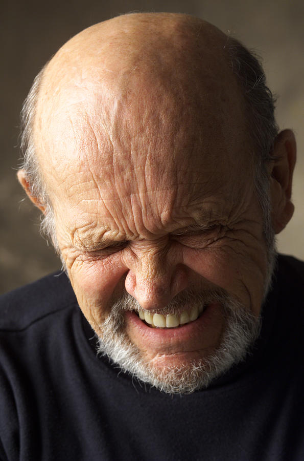 A Wrinkle Faced Balding Elderly Man Wearing A Dark Shirt Scrunches Up His Face While Closing His Eyes And Grimacing Photograph by Photodisc