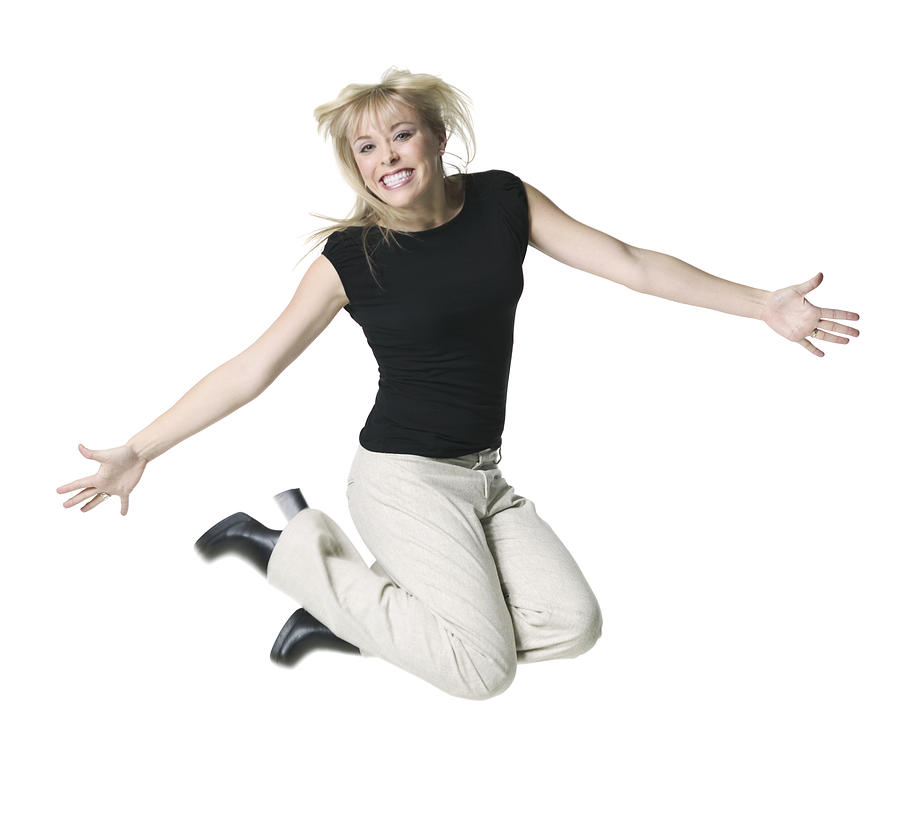 A Young Adult Blonde Female In Tan Pants And A Black Shirt Jumps Up And Smiles Photograph by Photodisc