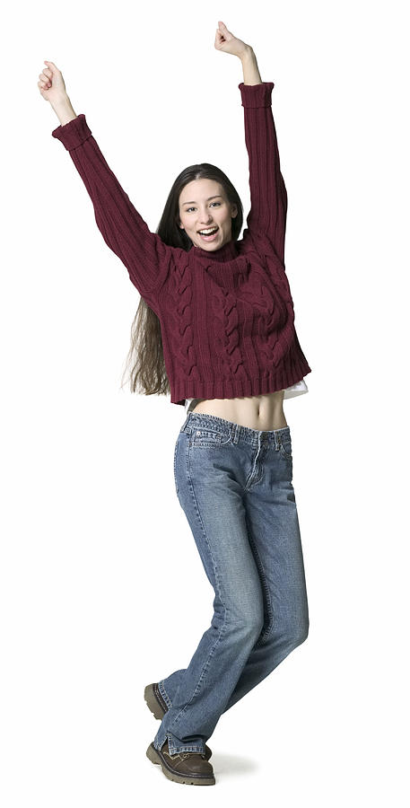 A Young Adult Female In Jeans And A Red Sweater Throws Up Her Arms While Dancing Photograph by Photodisc