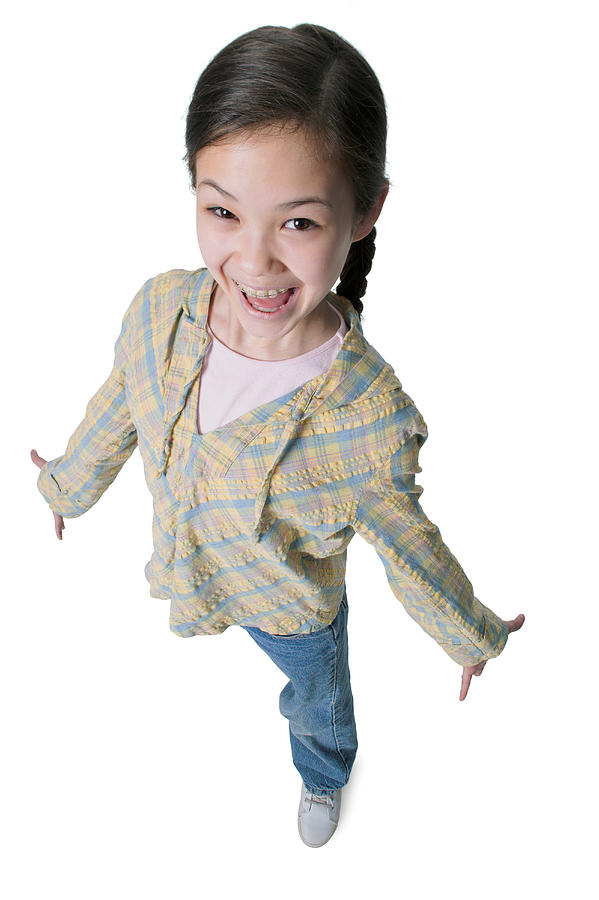 A Young Asian Girl In Jeans And A Green Shirt As She Spreads Out Her Arms And Smiles Up Into The Camera Photograph by Photodisc